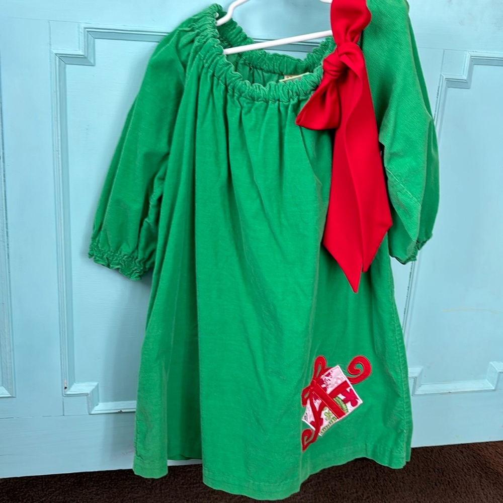 Green holiday corduroy dress with red bow accent.